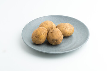 Fototapeta premium Fresh raw baby potatoes served on a grey ceramic plate isolated on white background