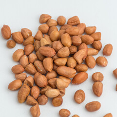 Obraz premium Pile of raw red peanuts with skin scattered on a plain white background