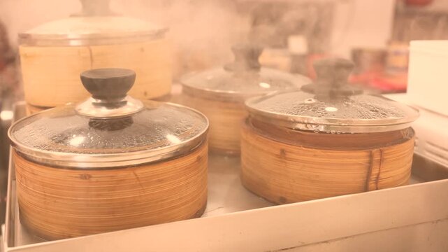 Bamboo steamers with glass lids arranged in an Asian street food kitchen, preparing dim sum and steamed dumplings popular across Bangkok, Singapore, Hong Kong, Malaysia, China and Japan