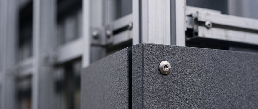 Modern architectural facade detail with metal fastener on textured panel and aluminum frame