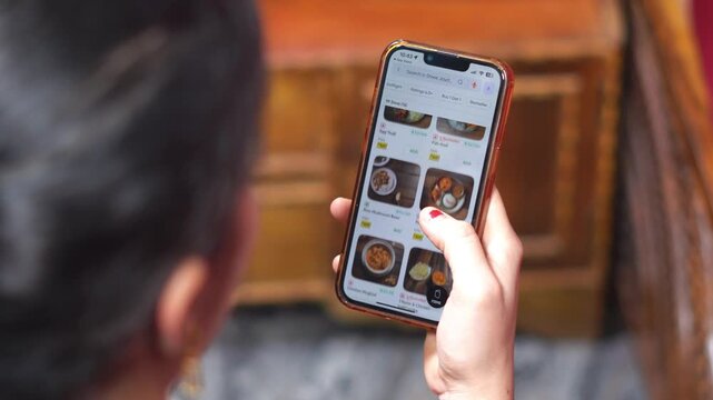 Indian Woman Ordering Food Online Using Smartphone App, Food Delivery and Digital Lifestyle.  Female Selecting Dishes and Ordering Food via Mobile Application Close Up. Ordering Dinner from Restaurant