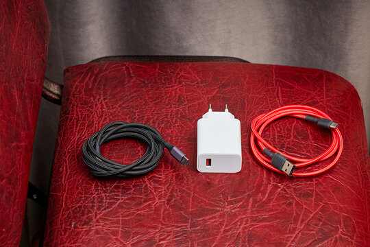 Two usb charging cables and adapter on red leather chair