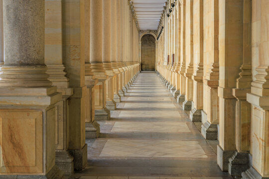 Grand architectural pillars in symmetrical stone corridor with sunlight