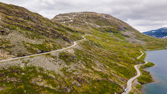 Aerial view of Djupvatnet lake with a winding road and a bus traveling along the rocky mountain slopes in Stranda Municipality, More og Romsdal, Norway.