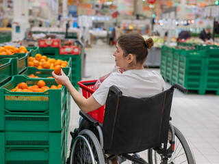 Obraz premium A Caucasian woman in a wheelchair buys fruit at a supermarket.