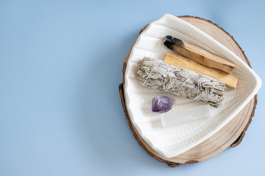 top view of sage bundle, crystal, and palo santo on ceramic dish for spiritual cleansing