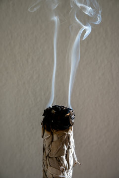 aromatic sage smudge stick burning with smoke in a calm, peaceful indoor setting