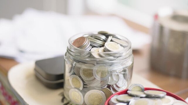 Close up of a glass jar full of mexican peso coins showing the concept of saving money