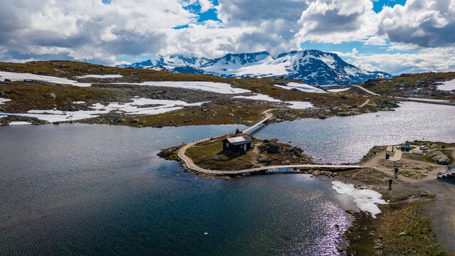 Aerial view of cabin at Sognefjellet, fv 55 scenic route surrounded by distant snow-capped mountains in Lom Municipality, Innlandet, Norway. Sognefjellet mountain pass, Norway