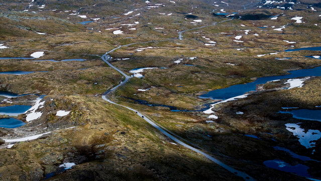 Aerial view of the winding scenic Sognefjellet mountain road pass along the famous fv55 route patches of snow and small lakes in Lom Municipality, Innlandet, Norway.