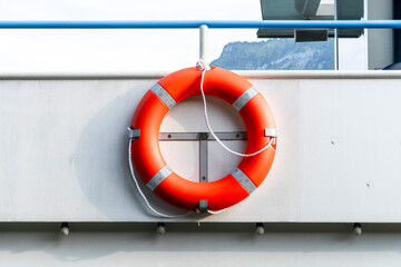 Bright orange lifebuoy on board a boat, illustrating maritime safety and the clean aesthetic of marine objects © Volha