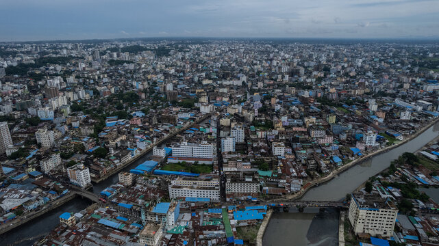 Aerial view of the dense urban landscape of Chittagong featuring a winding canal, buildings, and bridges spanning the waterway. Chittagong, Chittagong Division, Bangladesh.