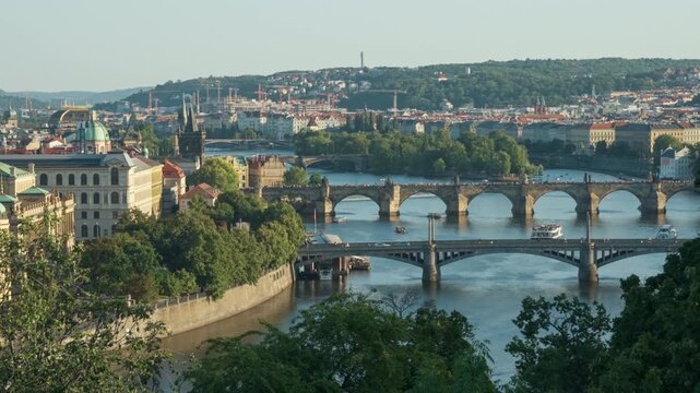 Historic Prague bridges span Vltava River in Czech Republic panoramic view. Tourist boats cruise along the scenic waterfront cityscape. Ideal European travel destination for summer vacation.