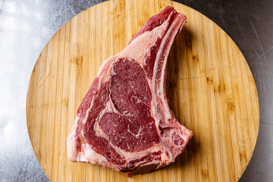 High-quality fresh beef steak cuts like Tomahawk, T-bone and Ribeye uncooked on wooden platters, with fresh ingredients