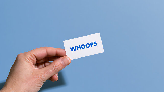 Human hand hold white card with text 'WHOOPS' in bold blue font on solid light blue background, concept of mistake or error