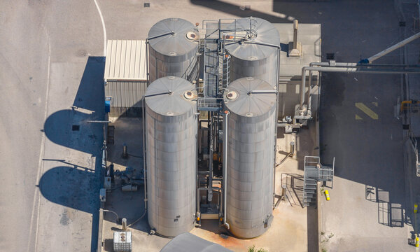 Aerial view of large industrial process tanks, pipelines and technical equipment at an aggregate processing and crushing facility in Valence, Auvergne-Rhone-Alpes, France.