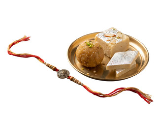 Fototapeta premium Handcrafted Raksha Bandhan rakhi displayed beside traditional Indian mithai on a brass plate, isolated as a transparent PNG festive gifting element.