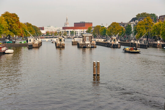 Scenic view of Amstel river with historic sluice gates, Magere Brug bridge and Stopera building in Amsterdam Netherlands