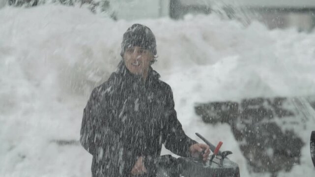 Man pushing snow blower during heavy winter blizzard