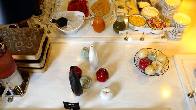 Buffet table with assorted drinks snacks and decorative ceramic fruits on marble surface