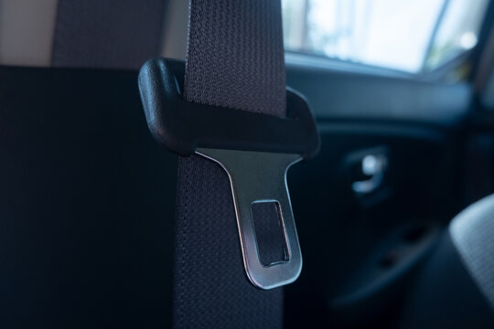 car door handle. close up selective focus on car seat safety belt buckles soft focus.  seat belt strap and metal latch hanging inside car interior with leather seat visible and soft light creating.