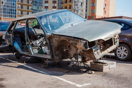 Automotive restoration project with dismantled vehicle body, chassis repair, components and maintenance.