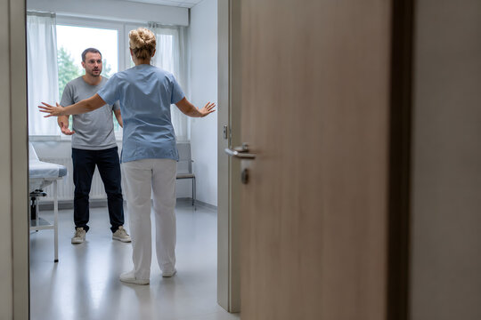 Healthcare professional de-escalating an anxious patient while maintaining a clear escape route in a hospital treatment room, illustrating workplace safety and crisis prevention.