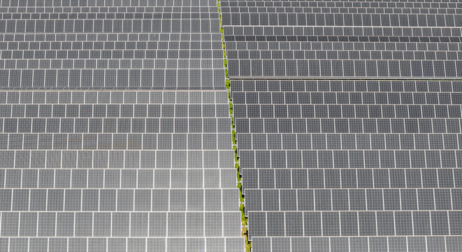Aerial view of a large solar power facility with rows of photovoltaic panels forming a geometric pattern in Le Pouzin, Auvergne-Rhone-Alpes, France.