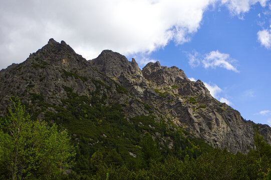 Majestic rugged rocky peaks of High Tatras mountains under a bright blue sky with white clouds. Impressive alpine landscape and nature.