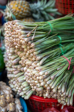 Bunch of tied fresh lemongrass stalks selling at local street marketplace, outdoor food market offering healthy greens for culinary purpose, ingredients for sale.