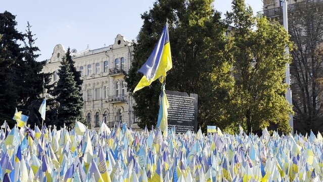 Many small blue-yellow flags with names of the dead war against russia. Memorial of the fallen soldiers, children, women in the capital of Ukraine. Concept of tragedy and misfortune. Close up