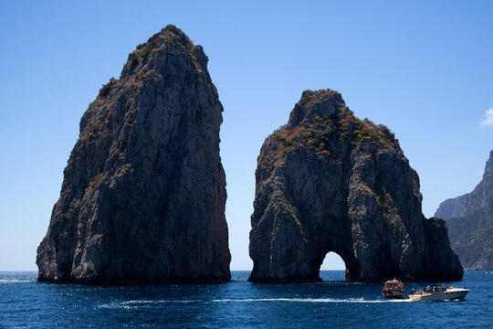 Limestone sea stacks natural arch boat passing blue water