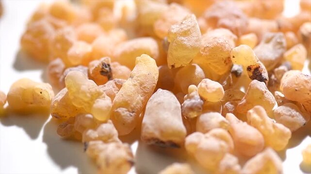 Frankincense olibanum resin, Boswellia sacra isolated on white background. Frankincense or olibanum aromatic resin used in incense and perfumes, fragrance, rotating backdrop, macro shot. 