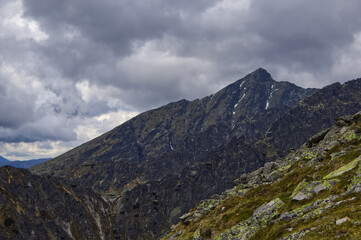 Fototapeta premium Imposing dark mountain peak in the High Tatras dominating the landscape under a gloomy, heavy cloudy sky before a summer storm.