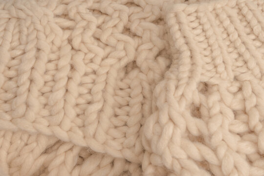 A fragment of beige knitted fabric, knitted from white sheep wool.
