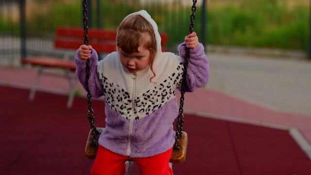 Child enjoying a swing at an outdoor playground, gripping the chains and moving through a playful moment of childhood recreation