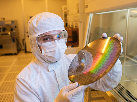 Cleanroom operator holding a silicon wafer in a semiconductor fab