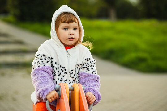 Child playing on a spring rocker in a park, moving from seated riding to standing while enjoying outdoor playground activity