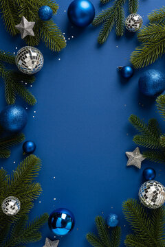 Blue Christmas ornaments and evergreen branches framing a Merry Christmas and Happy New Year vertical scene with blank space in the middle