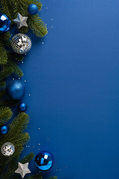 Blue Christmas ornament display with evergreen branch on blue vertical background for Merry Christmas and Happy New Year