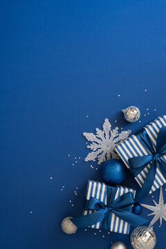 Merry Christmas blue gift composition with ribbon, ornament and happy New Year decorations on vertical dark blue desk