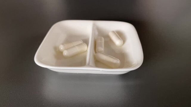 Patient Preparing for Medication with White Capsules in a Dish