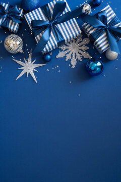 Blue Christmas gift boxes with ribbons and ornaments for Merry Christmas and Happy New Year on vertical shiny blue space for text