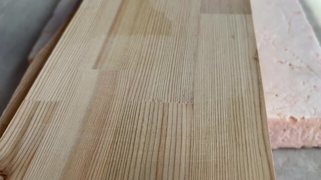 a worker's gloved hand checking the smoothness of a sanded wooden board. Carpentry, woodworking, or home renovation