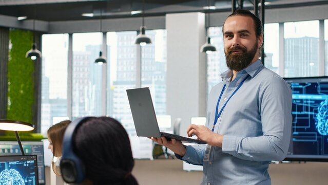 Cheerful programmer codes AI algorithms on a laptop to debug software issues and improve system stability, configuring settings on a notebook during application testing in a startup office.