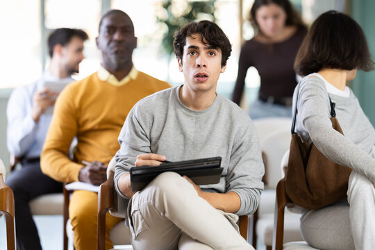 Guy listens attentively to teacher and takes notes in notebook during a professional development course