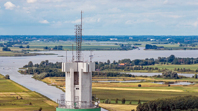 Aerial view of the ViaData Toren telecommunications and data center tower rising above the flat, green landscape, winding canals, and agricultural fields of Tjerkgaast, Friesland, Netherlands.