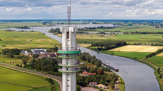 Aerial view of the ViaData Toren communication tower and data center, rising above the green fields, canal, and rural landscape of Tjerkgaast, Friesland, Netherlands.