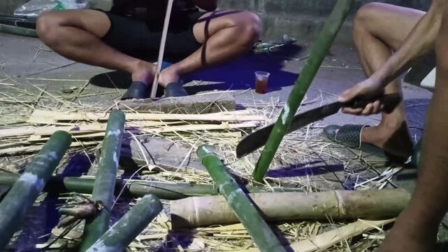 craftsmen splitting bamboo poles manually using machete for traditional handcraft