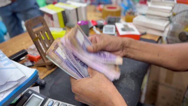 Hands Counting Bangladeshi Taka Banknotes at Local SME Business Counter in Bangladesh